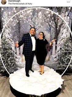 a man and woman posing for a photo in front of a snow scene with trees