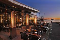 an outdoor dining area with tables, chairs and lights on the side of the building