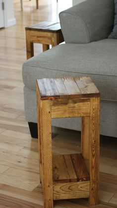 a wooden table sitting on top of a hard wood floor next to a gray couch