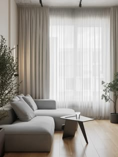 a living room filled with furniture and a large window covered in sheer draping