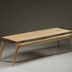 a wooden table sitting on top of a white floor next to a gray wall in the background