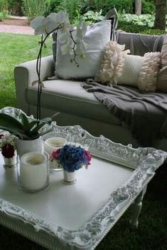 a table with flowers and candles on it in front of a couch, coffee table