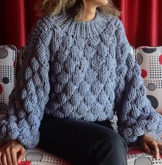 a woman sitting on top of a couch wearing a blue sweater