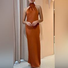 a woman standing in front of a mirror wearing an orange dress