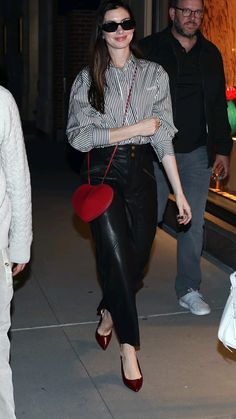 a woman in black and white shirt carrying a red purse