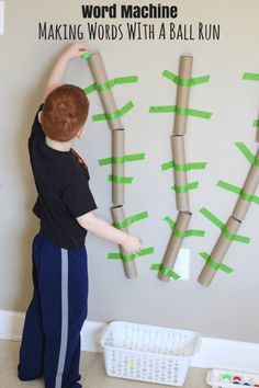 a young boy standing in front of a bulletin board with green arrows on it and the words making words with a ball run