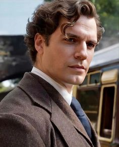 a close up of a person wearing a suit and tie with a train in the background