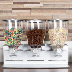 three dispensers filled with different types of cereal on top of a counter