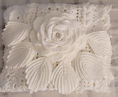 a white crocheted pillow with a flower on it