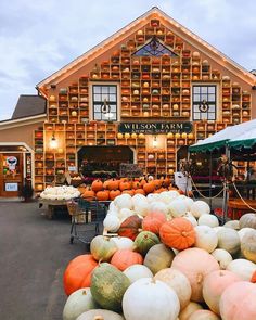 pumpkins and gourds for sale in front of a large wooden building with windows