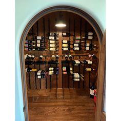 an arched doorway leads to a wine cellar with many bottles of wine on the shelves