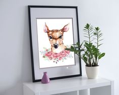 a painting of a deer with pink flowers on it's head is displayed next to a potted plant