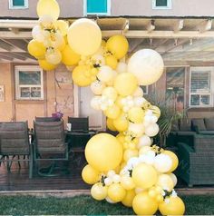 yellow and white balloons are hanging from the side of a house