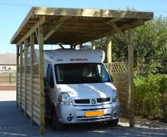 a white van is parked under a wooden structure with a roof on it's side