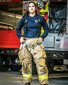 a woman standing in front of a firetruck with her hands on her hips