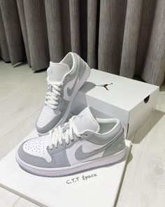 a pair of white and grey sneakers sitting on top of a box