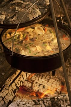 the food is being cooked on the grill in the open fire pit with tongs