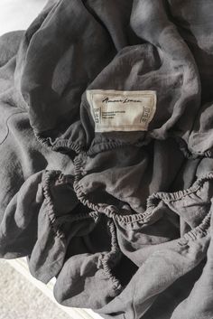 the back of a black jacket with ruffles and a label on it's side