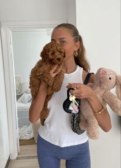 a woman is holding two stuffed animals in her hands and she is looking at the camera