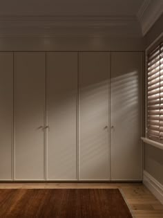 an empty room with white cupboards and wooden floors