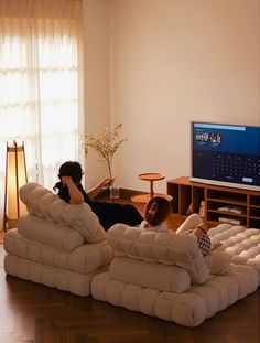 a woman laying on the back of a couch in front of a flat screen tv