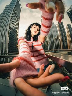 a woman in pink and white sweater holding up her hand