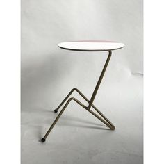 a small table with a white top and metal frame on it's legs, against a plain background