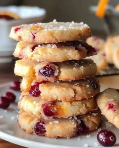 a stack of cookies sitting on top of a white plate next to some cranberries