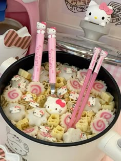 two hello kitty straws are in a cup with noodles and other food on the table