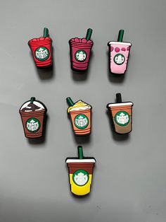 six starbucks cup magnets on a gray surface