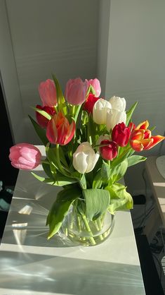 a vase filled with lots of different colored tulips on top of a table