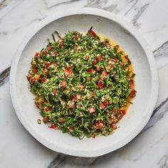 a white bowl filled with salad on top of a marble counter