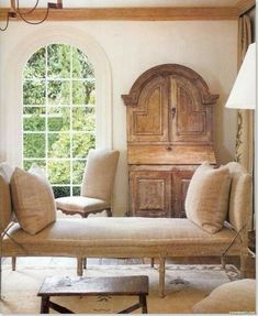 a living room filled with furniture and a large window covered in windowsills next to a wooden dresser