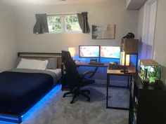 a bed room with a neatly made bed next to a desk and two monitors on the wall