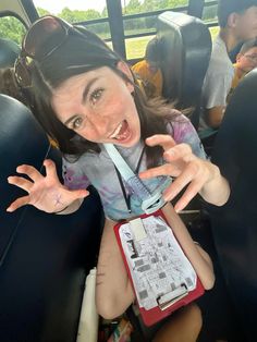 a woman sitting in the back seat of a bus with her hand up and mouth open