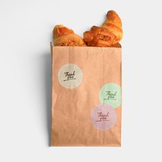 two croissants in a brown paper bag with stickers on the side