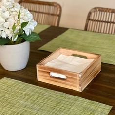 a wooden box sitting on top of a table next to a vase filled with white flowers