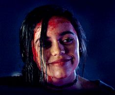 a close up of a person with blood on her face and hair in the dark