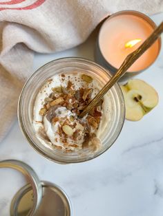 a glass jar filled with food next to an apple slice and two candles on a table