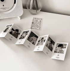 an open photo album sitting on top of a table next to a clock and vase