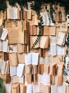 many books are stacked on top of each other with ivy growing up the wall behind them