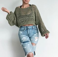 a woman wearing ripped jeans and a green knitted sweater is posing for the camera