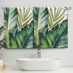 a white bowl sitting on top of a counter next to a green leafy wall hanging