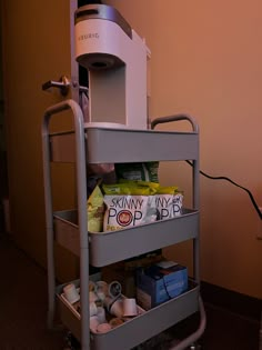 a small cart with some food on it and a coffee maker in the back ground