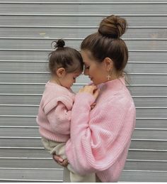 two women in pink sweaters standing next to each other with their arms around one another