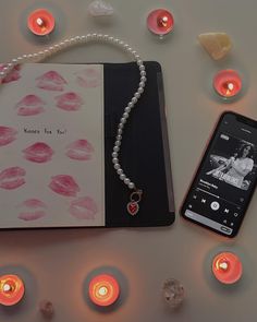 an open notebook with a cell phone next to it on a table surrounded by candles