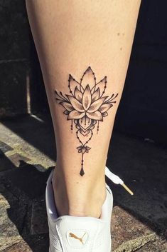 a woman's foot with a flower tattoo on the side of her leg and an arrow