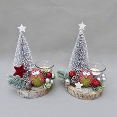 two glass candlesticks decorated with christmas decorations