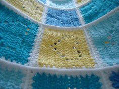 a crocheted dishcloth with blue, yellow and white squares on it's sides