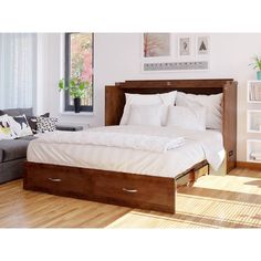 a bed sitting on top of a hard wood floor next to a couch and window